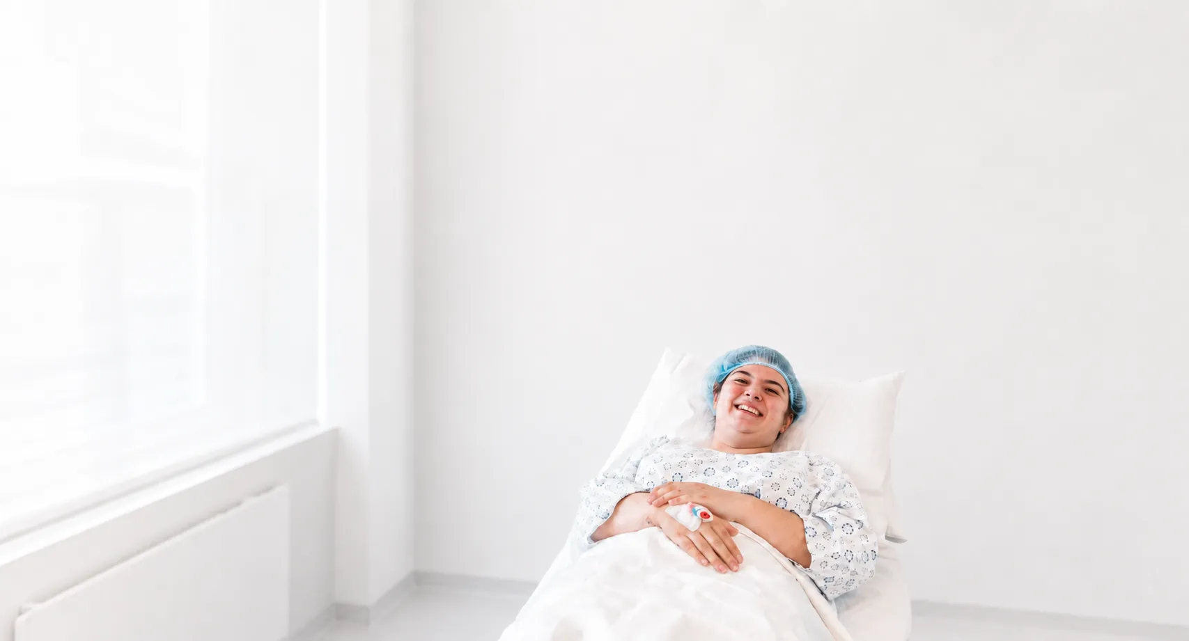 Lächelnde Patientin im Krankenbett nach der Behandlung